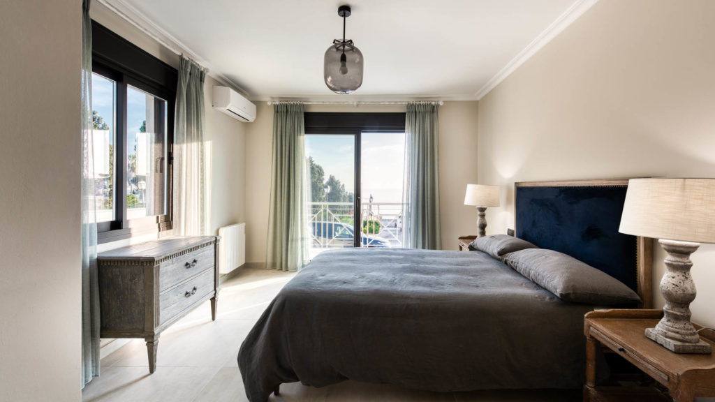 Modern bedroom with floor to ceiling windows and dark furnishings in Marbella