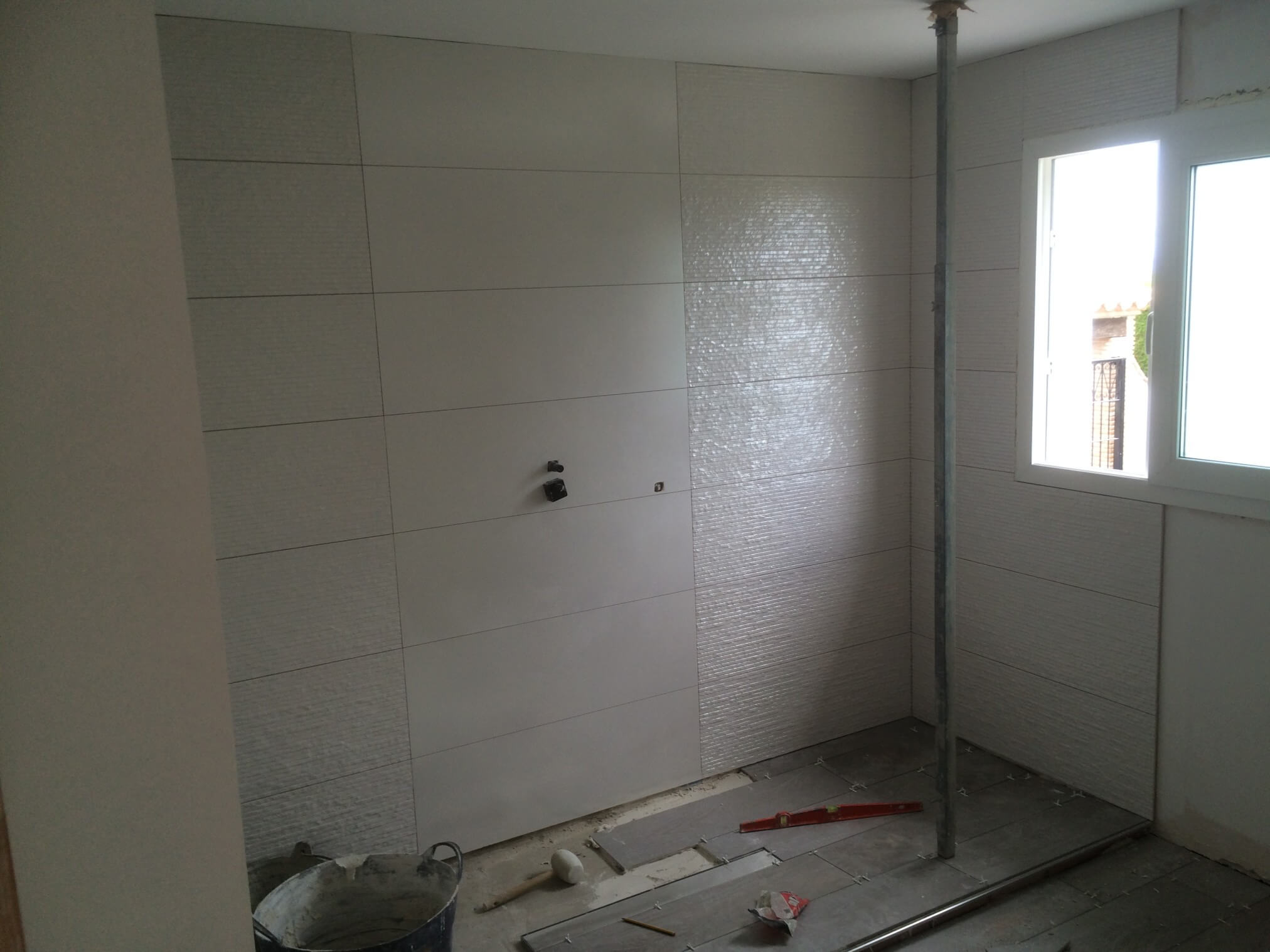 Large tiles being applied to the bathroom walls