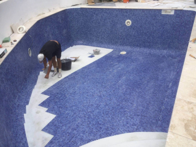 Pool being tiled with blue tiles