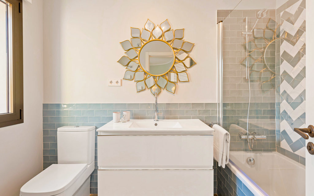 Stylish grey toned bathroom with herringbone tiles and feature mirror