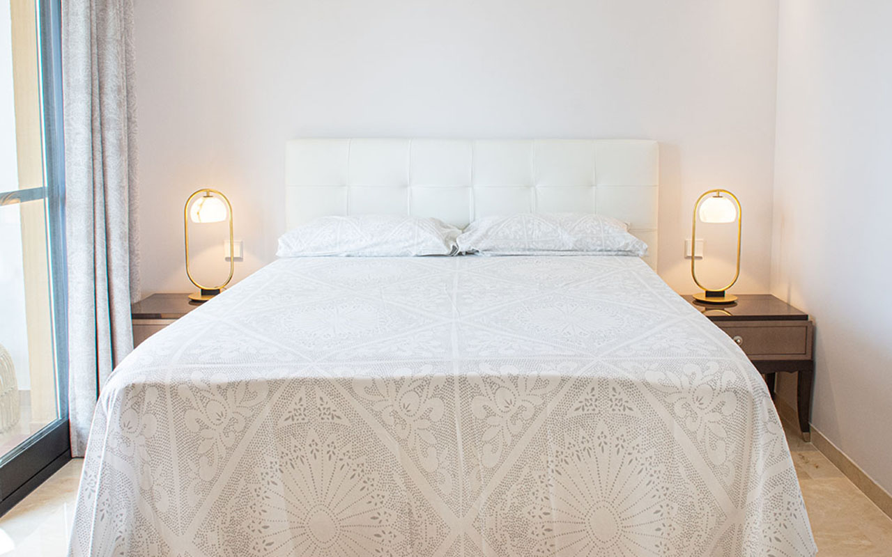 Stylish white bed and modern bedside tables and lamps
