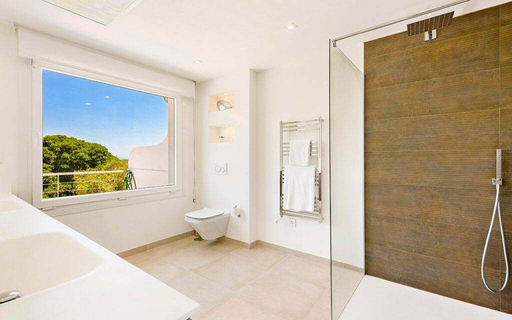 Stylish bathroom with frameless shower and brown tiles