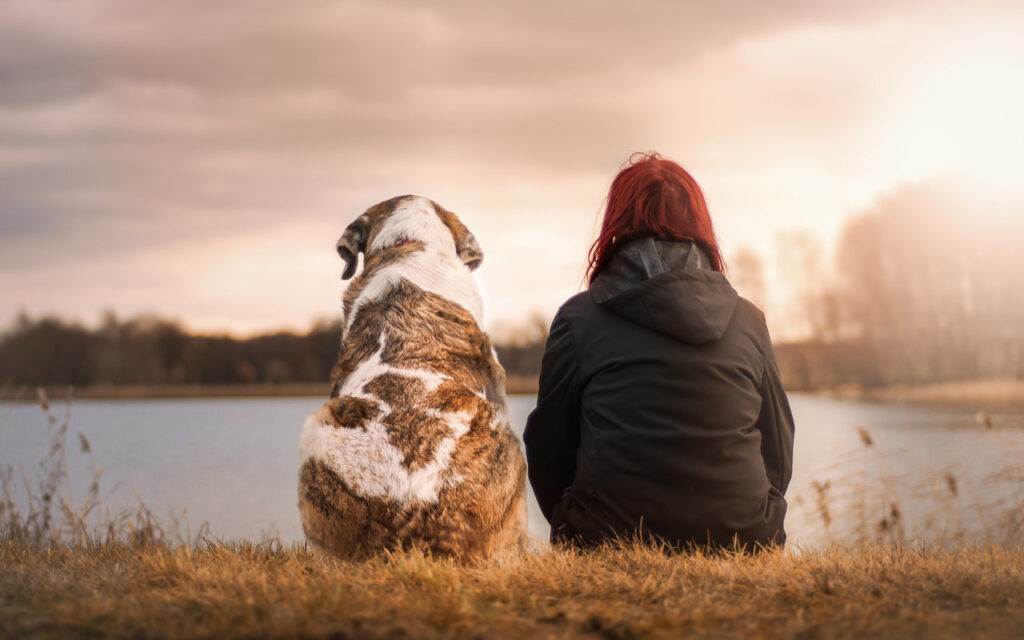 Lady sitting next to her dog in nature