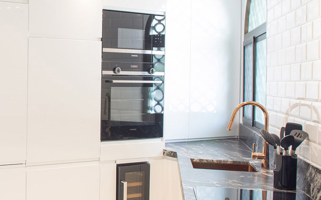 white kitchen with black marble and copper sink