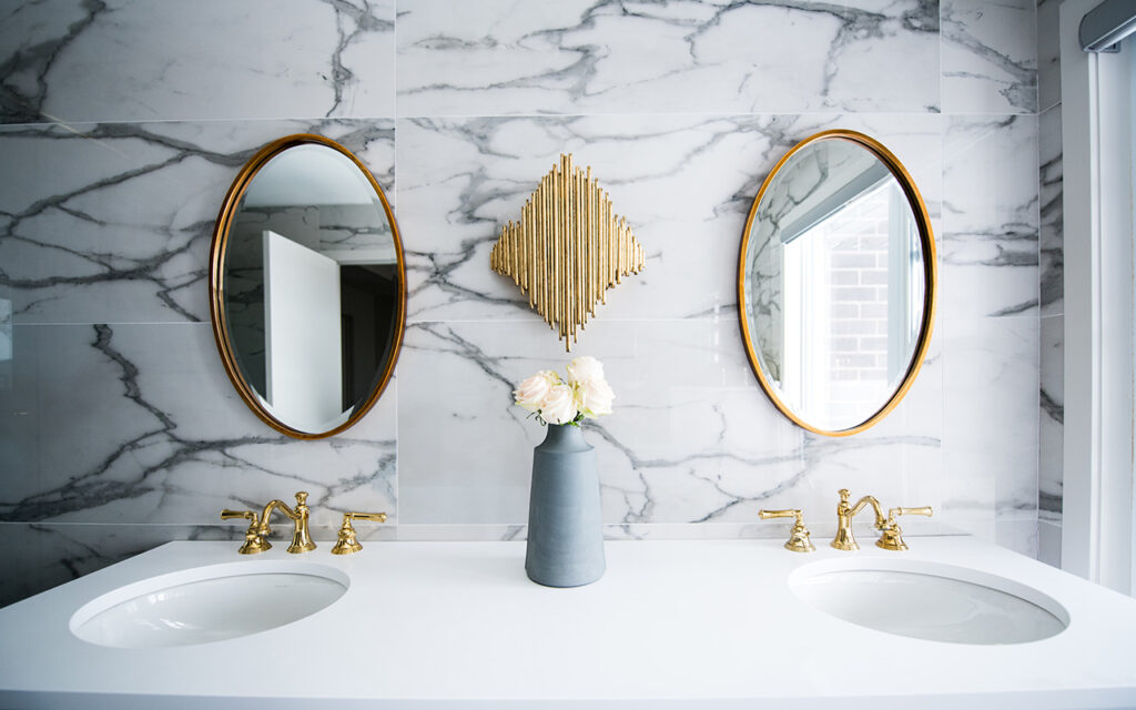 Bathroom vanity with white marble walls and gold accents