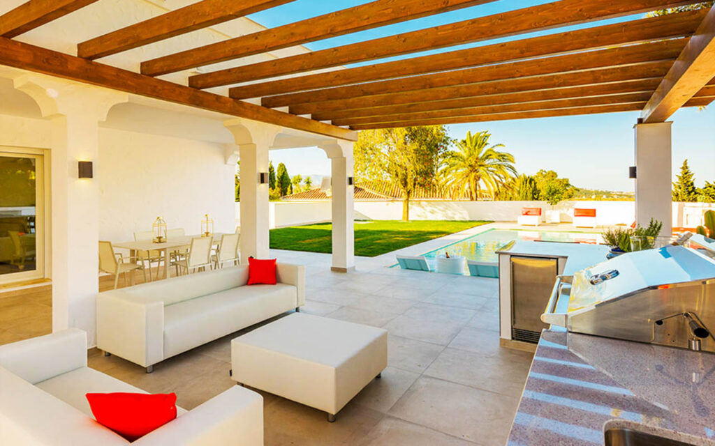 Pergola beside swimming pool with outdoor kitchen barbeque and chill out area by ProMAs building in Marbella Costa del Sol