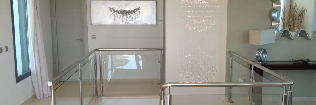 Modern interior with a glass railing, artwork, and decorative lighting fixtures.