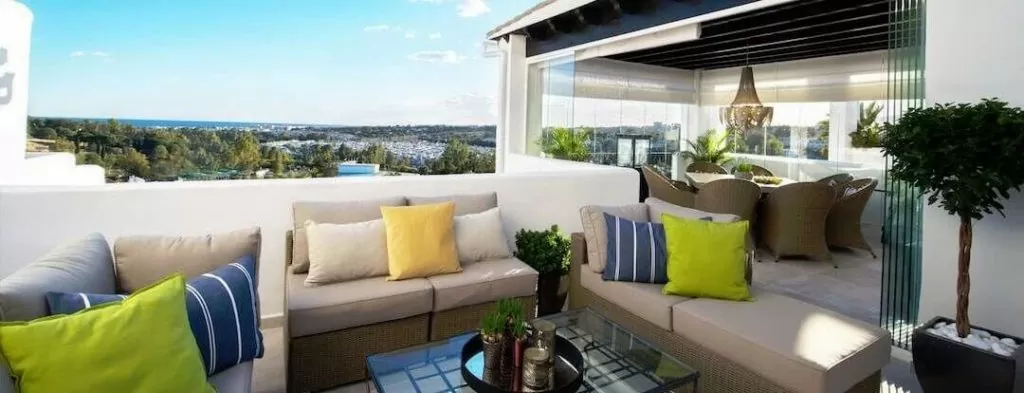 Stylish balcony with lounge seating, vibrant cushions, and a view of the landscape.