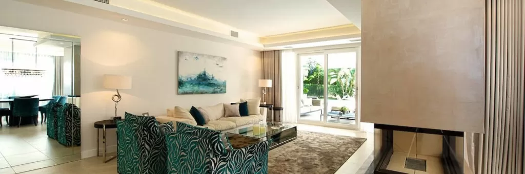 Bright, modern living room featuring patterned furniture, artwork, and large glass doors.